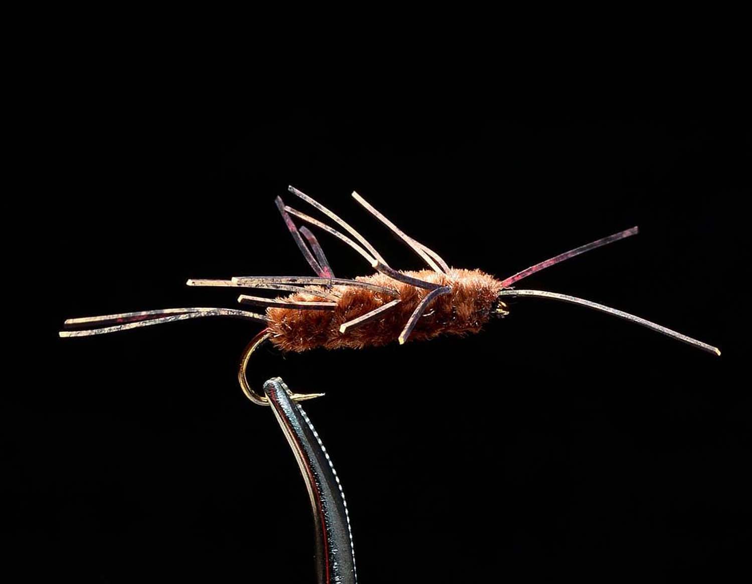 Brown Pat's Rubberleg Stonefly nymph fishing fly with rubber legs against black background
